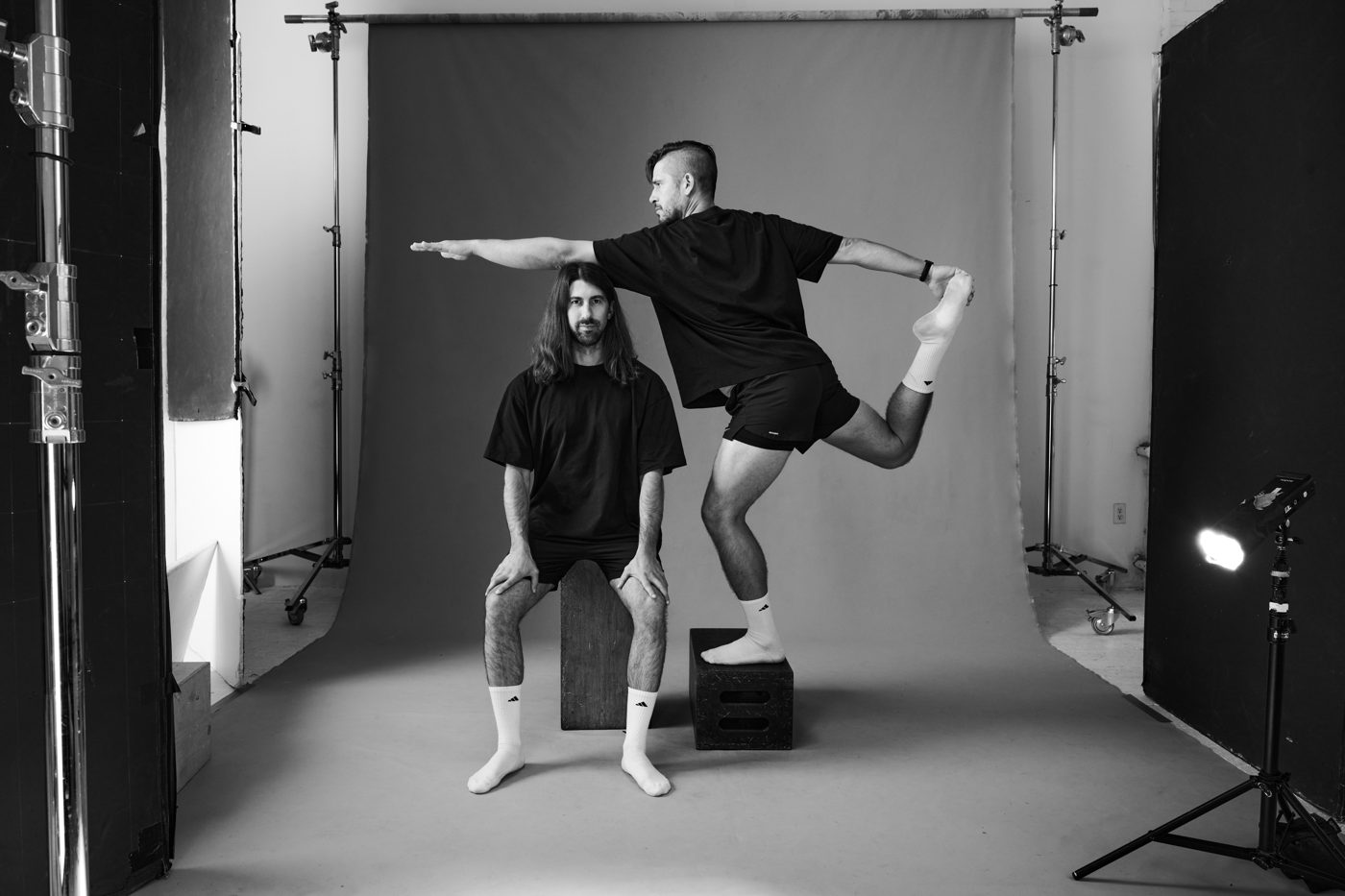 Black and white, one seated on an apple box, one in an airplane pose
