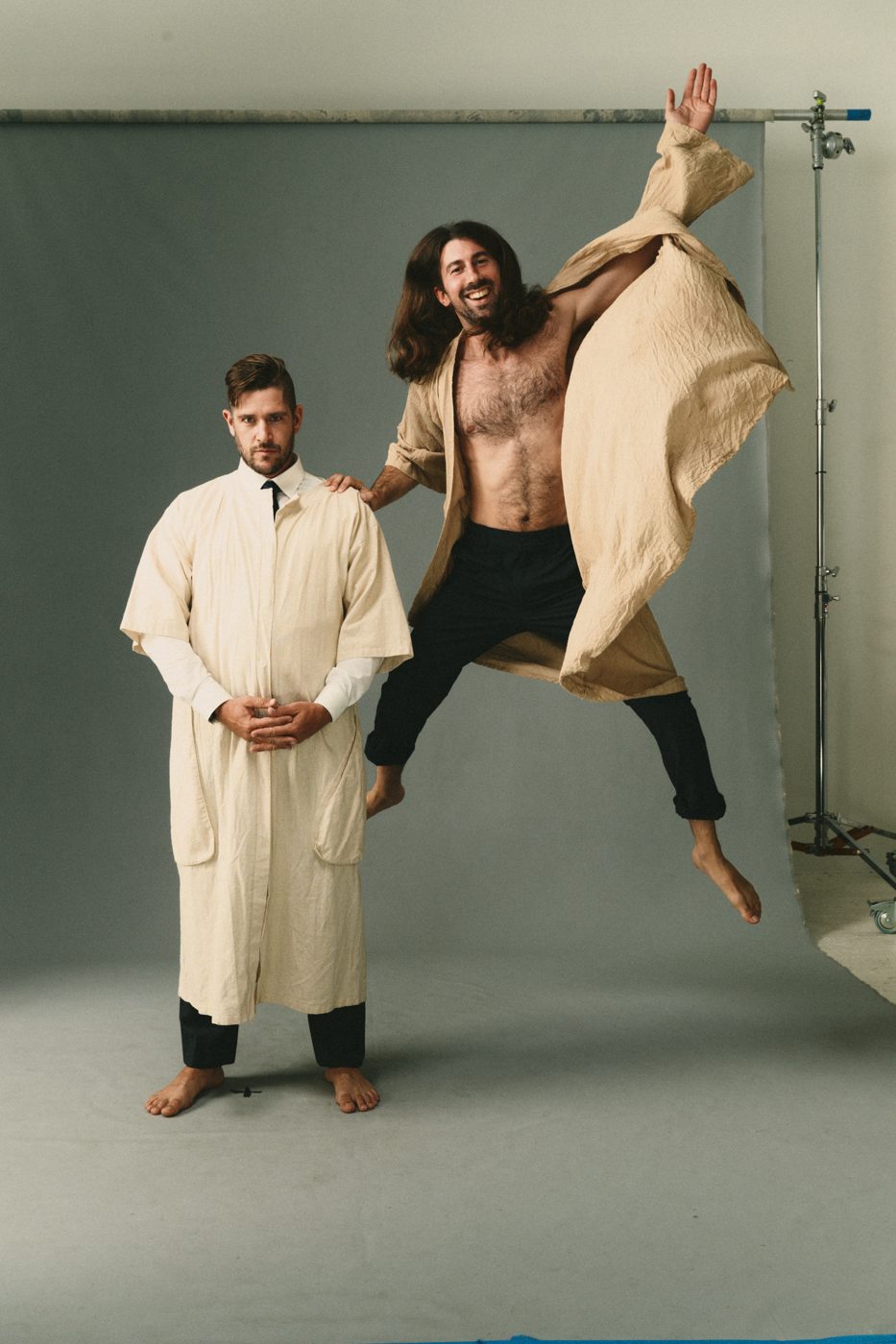 One in a cream robe stands still while the other leaps in a tan kimono