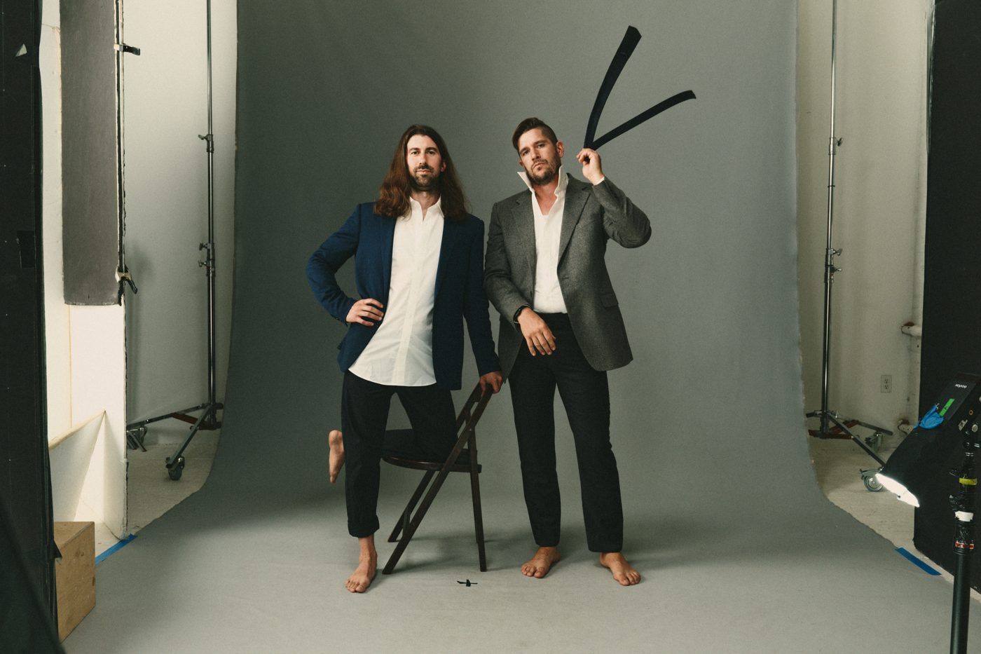 Suits, one holding a C-stand arm overhead