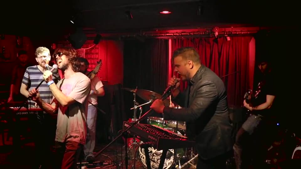 Sweet Synth Prince live, 24 March 2019 — two singers on mics in a red-lit club, five players on stage