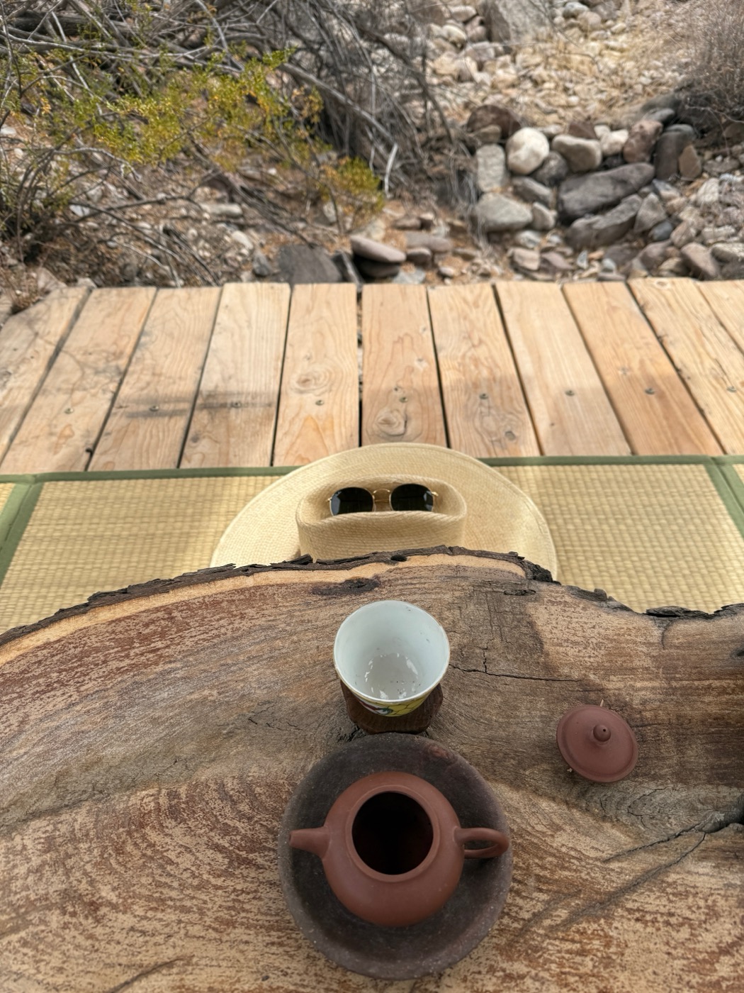 A shadow falling across desert ground, tea in hand